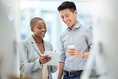 A Black woman and Asian man are discussing work while looking at a tablet computer